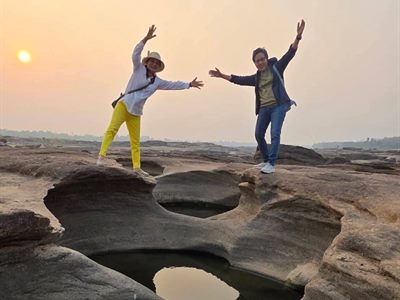 ลูกค้ากางแขนถ่ายรูปบนลานหินสามพันโบกยามพระอาทิตย์ตก